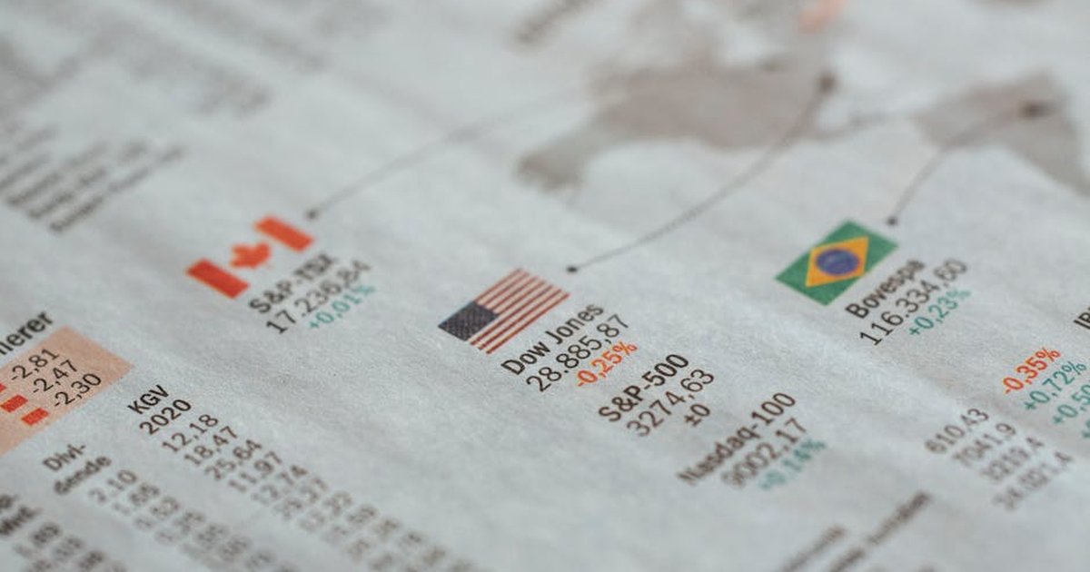Detailed close-up of a newspaper displaying global financial market statistics and country flags.