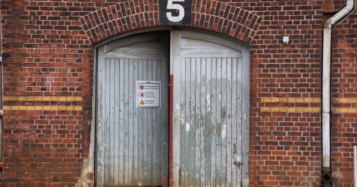 Historic brick facade in Hamburg featuring weathered wooden doors and numbered sign.