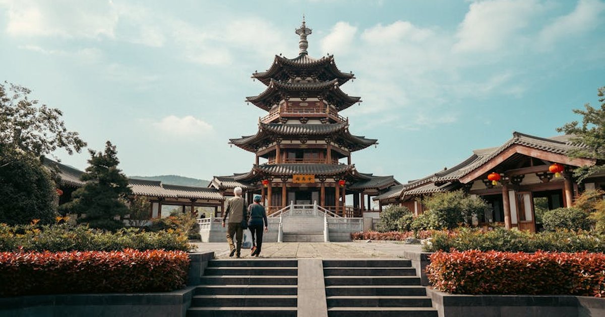Photograph of the Jin Wu Pavilion in Nanjing, showcasing traditional Chinese architecture with two people walking towards it.
