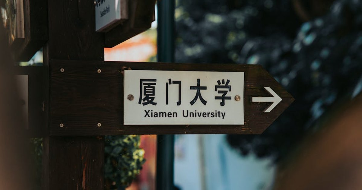 Directional sign pointing to Xiamen University in an outdoor setting.