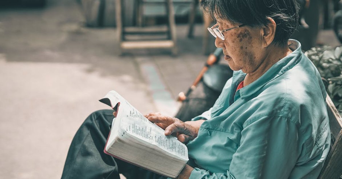 Senior man reading a book outdoors in Beijing, conveying a peaceful and studious atmosphere.