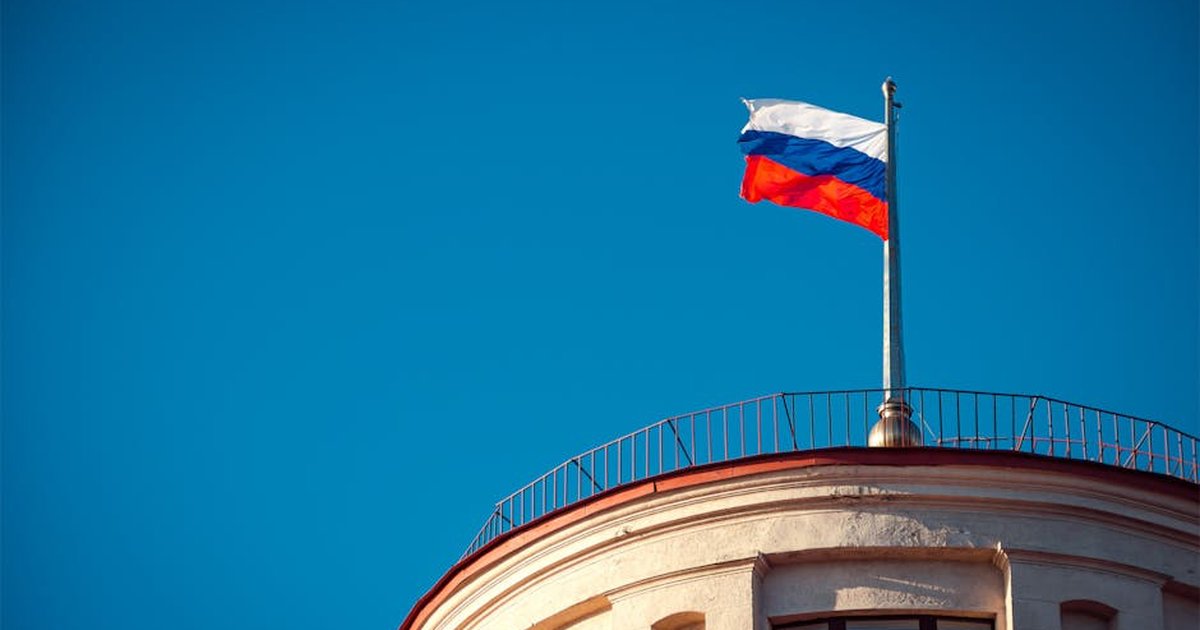 Russian national flag waving on a building in St. Petersburg under clear skies.