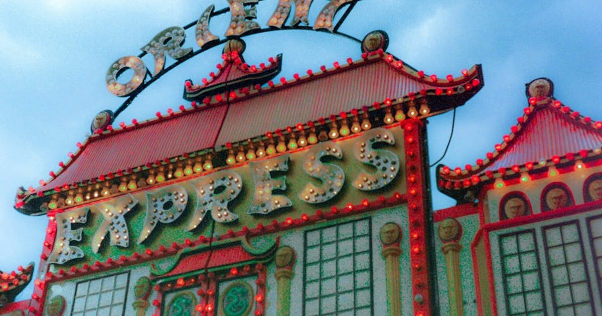 A vibrant photo of an illuminated Orient Express ride with colorful lights at a festival.
