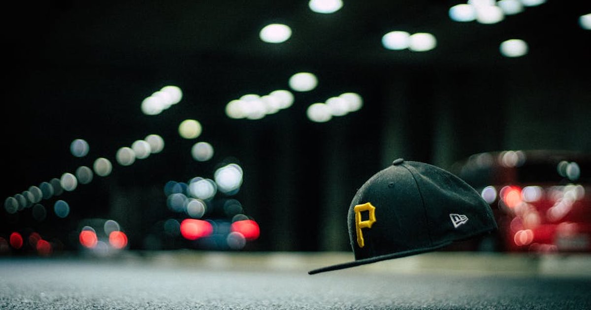 A levitating cap with letter 'P' floats above asphalt, surrounded by night street bokeh lights.