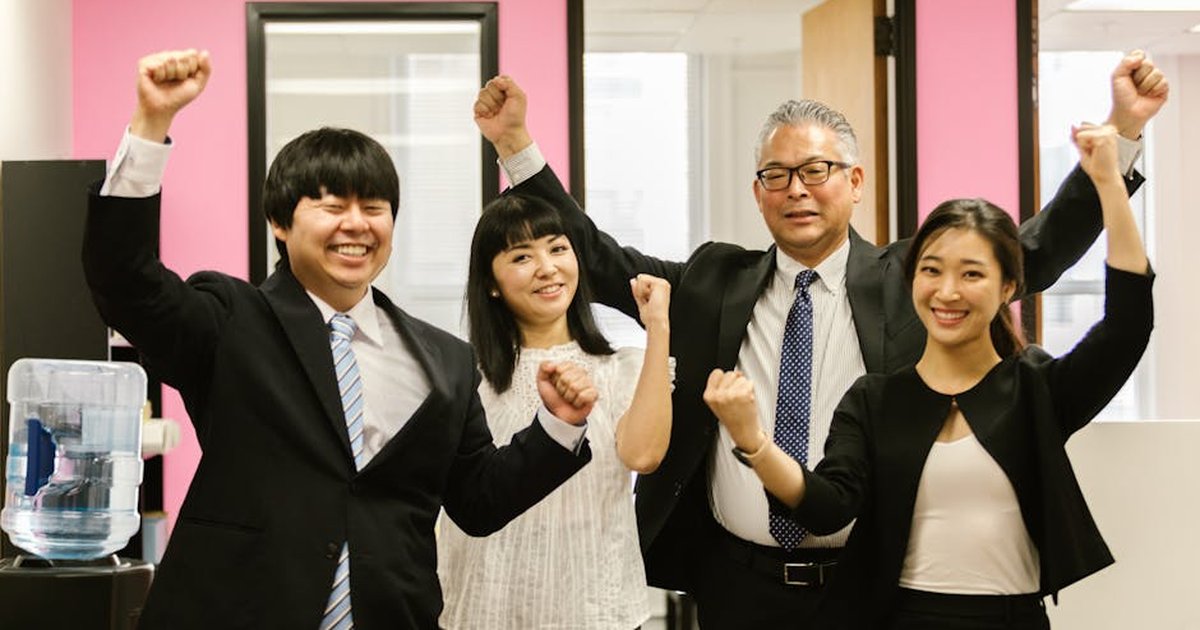 Diverse team of smiling coworkers celebrating success together in an office setting.
