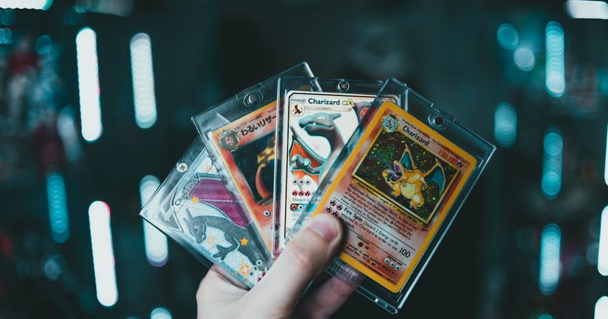 A hand holds collectible Charizard Pokemon cards with a blurred bokeh background. Perfect for trading card enthusiasts.