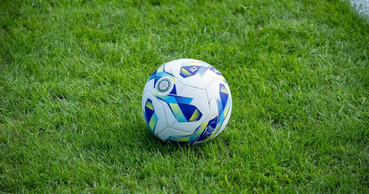 A detailed view of a soccer ball resting on a lush green grass field.