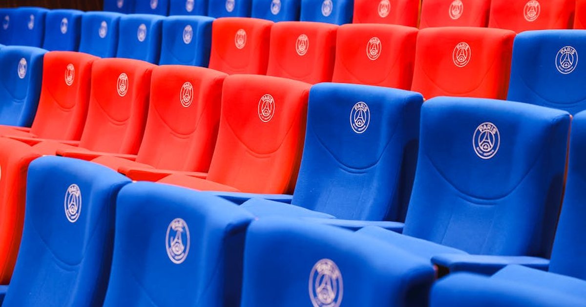 Rows of red and blue stadium seats featuring Paris emblems, vibrant and empty.