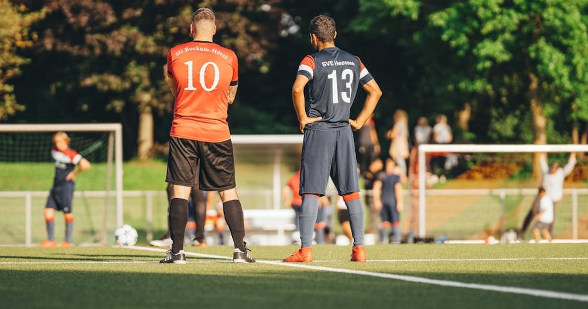 Soccer players in team jerseys standing on the field ready for the game.