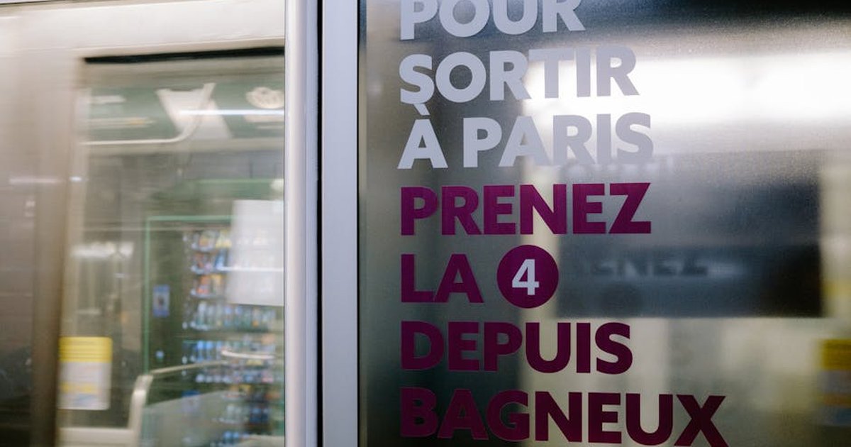 Close-up of Paris metro sign with blurred train in motion, vibrant color contrast.