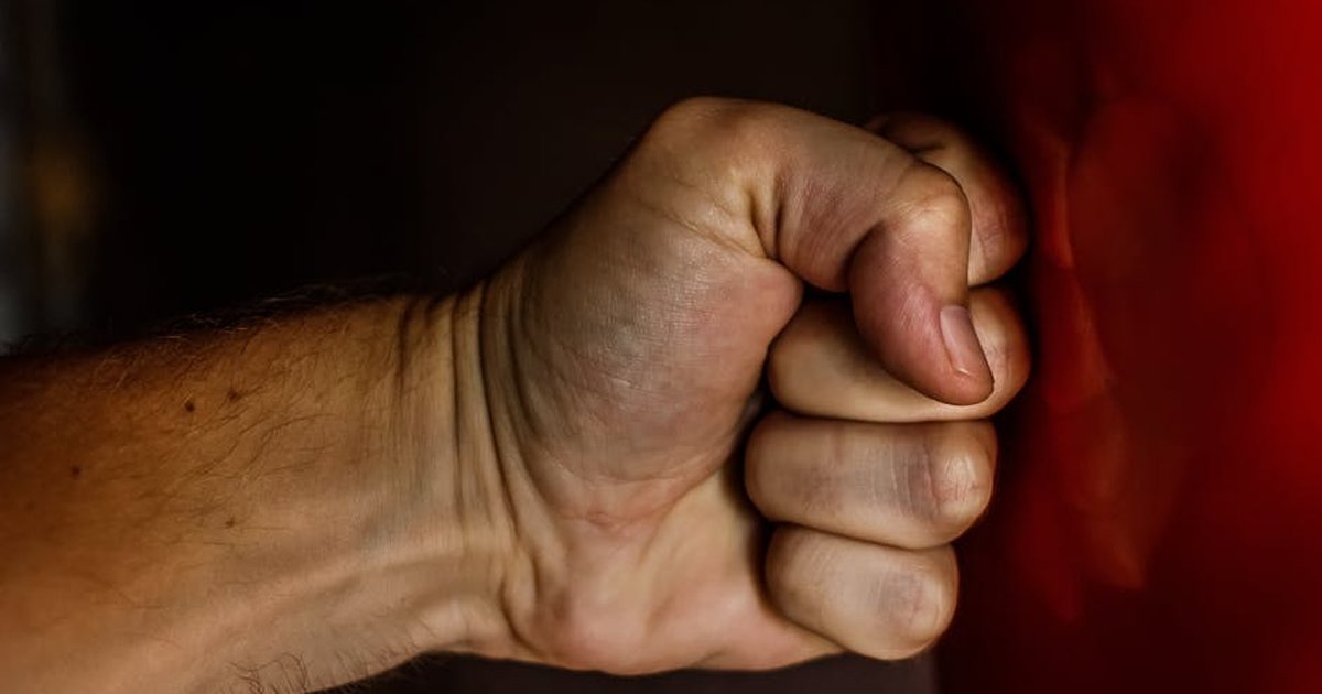A detailed close-up of a clenched fist striking a red surface showcasing strength.