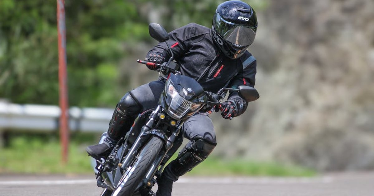 A biker in full gear leaning into a sharp curve on a scenic road, showcasing motorcycle agility and skill.