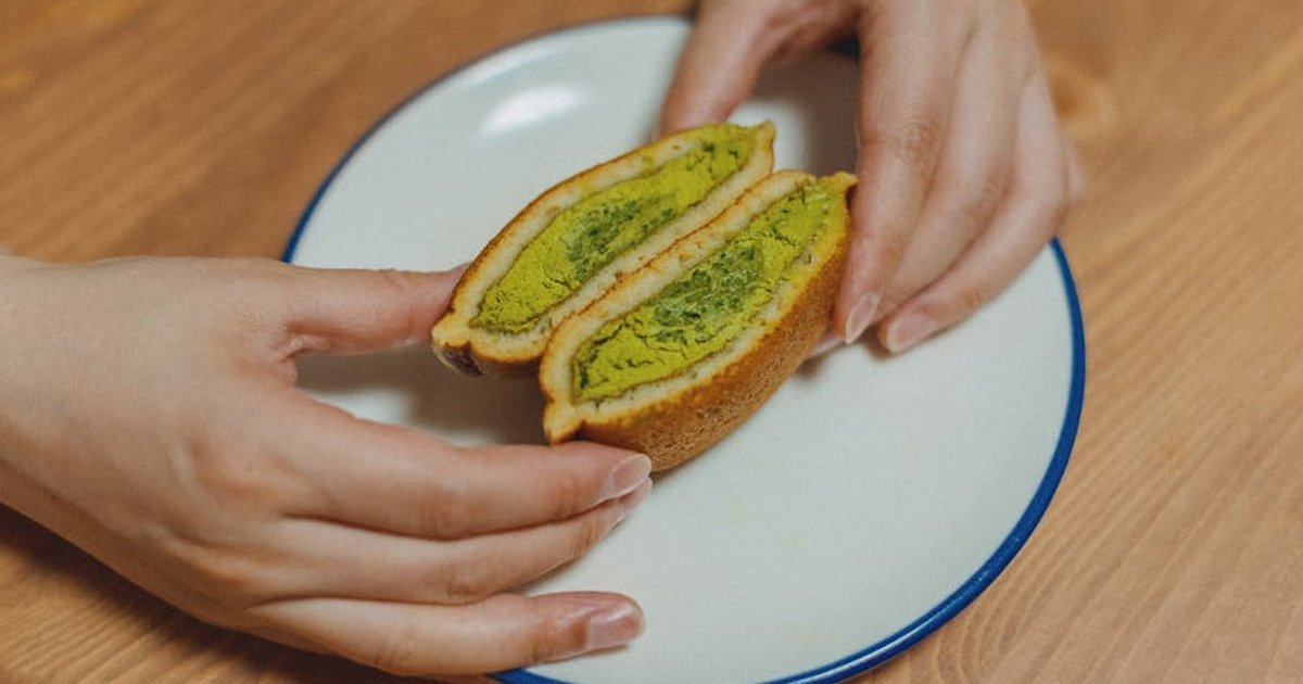 A close-up of matcha-filled dorayaki on a plate being held by hands, offering a traditional Japanese dessert experience.