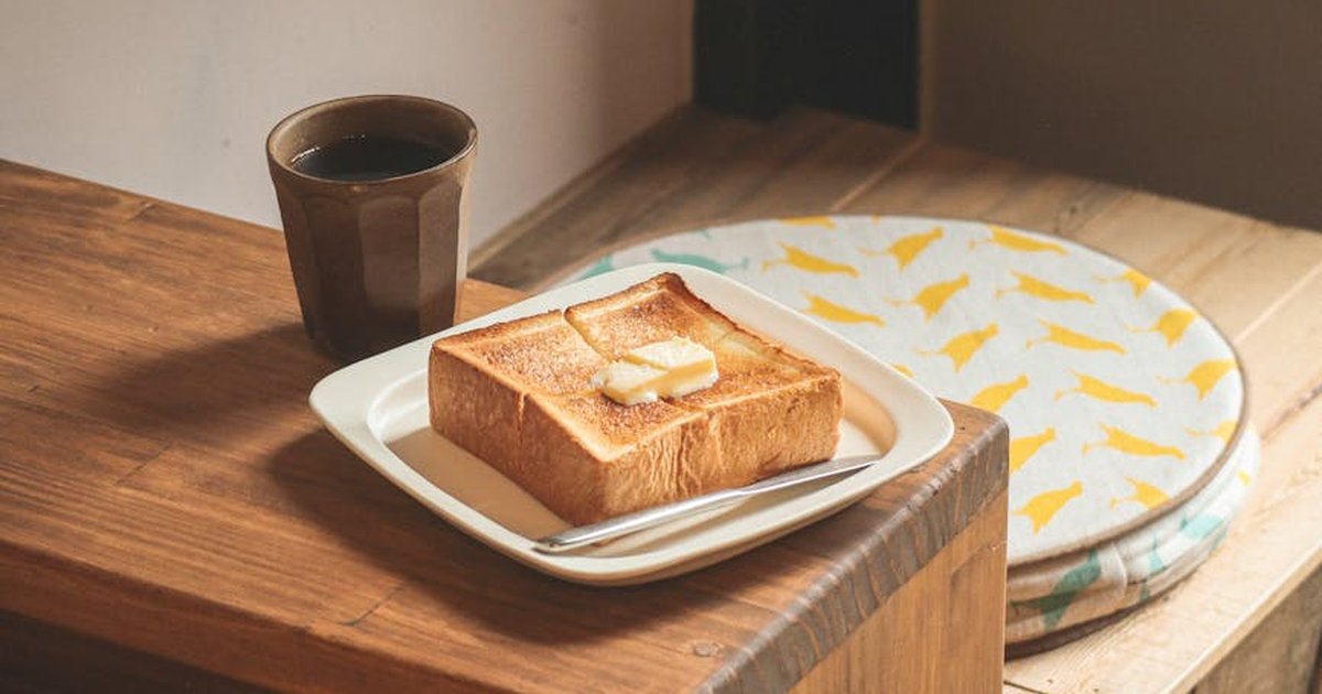 A cozy breakfast setting featuring buttered toast and a cup of coffee on a wooden table.