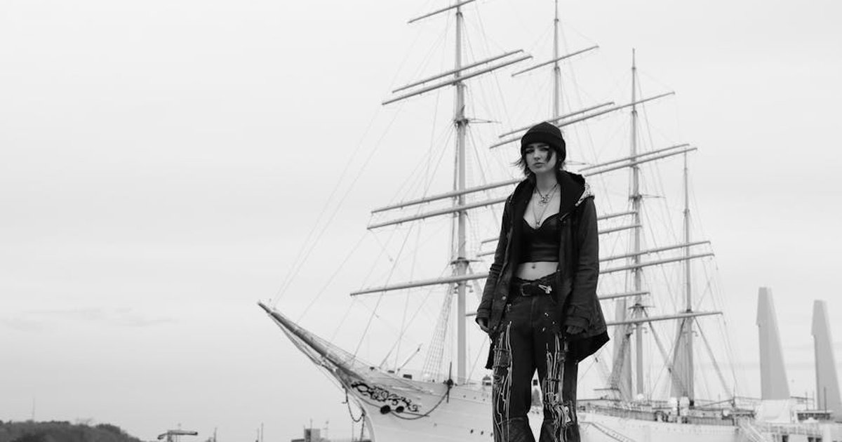 Black and white photo of a fashion model standing near a sailboat in Gothenburg, Sweden.