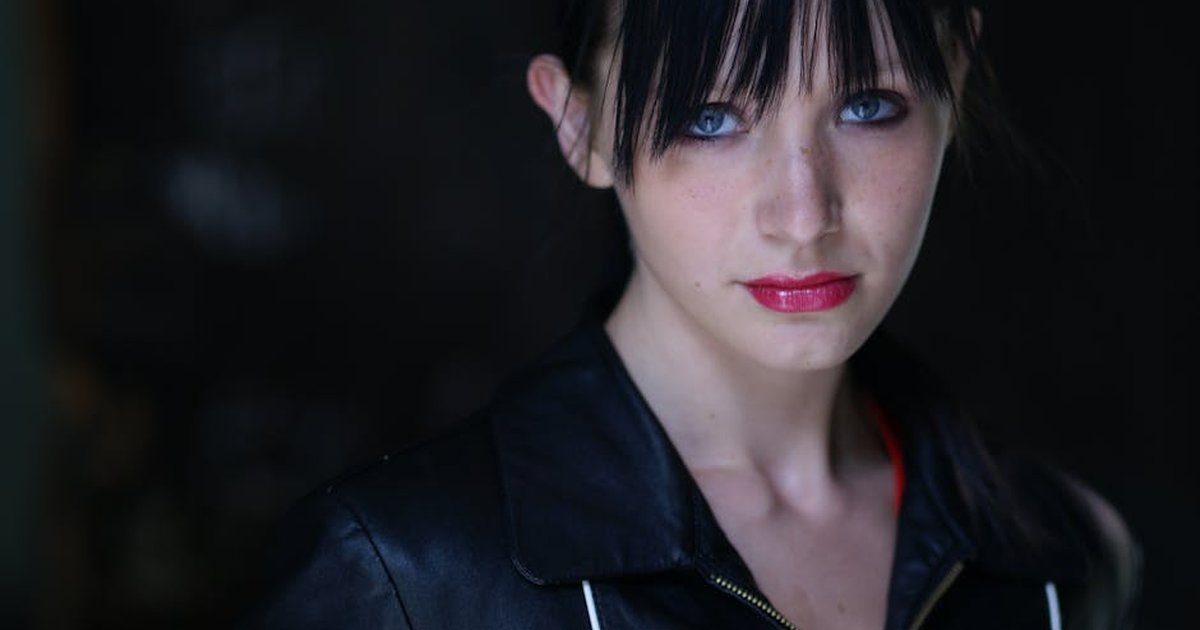 Portrait of a young woman with black hair and blue eyes wearing a black leather jacket.