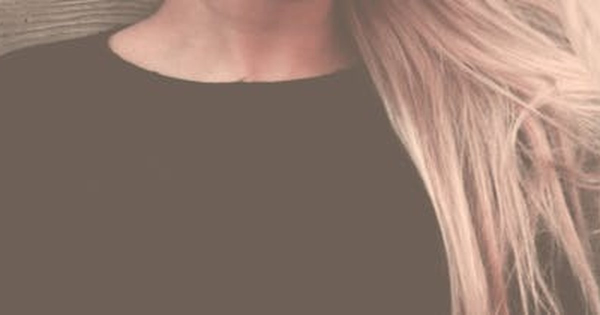 Close-up portrait of a woman with long, flowing blonde hair against a textured background.