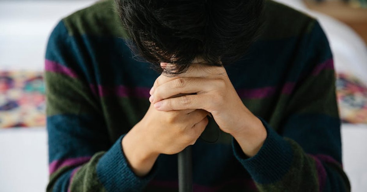 Young adult resting with hands clasped over a walking stick, conveying a sense of contemplation.