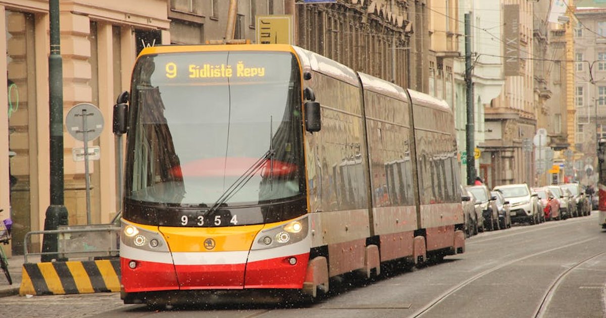 Tram number 9 moves through a bustling urban street in Prague, showcasing city life and transportation.