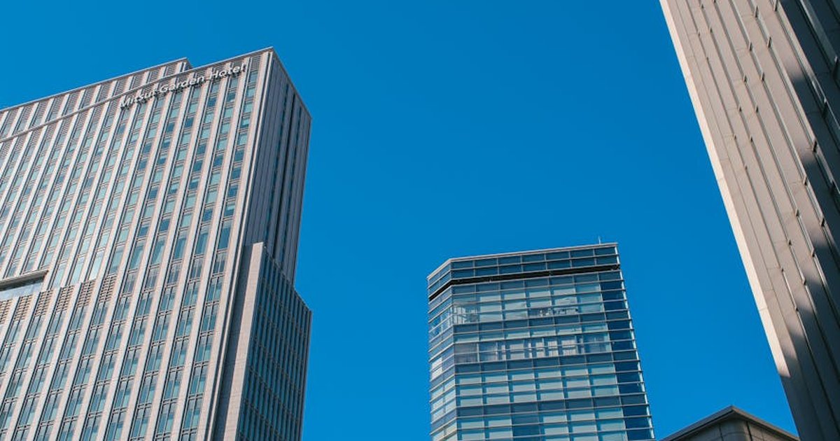 Dynamic view of modern skyscrapers rising against a clear blue sky, showcasing urban architecture.
