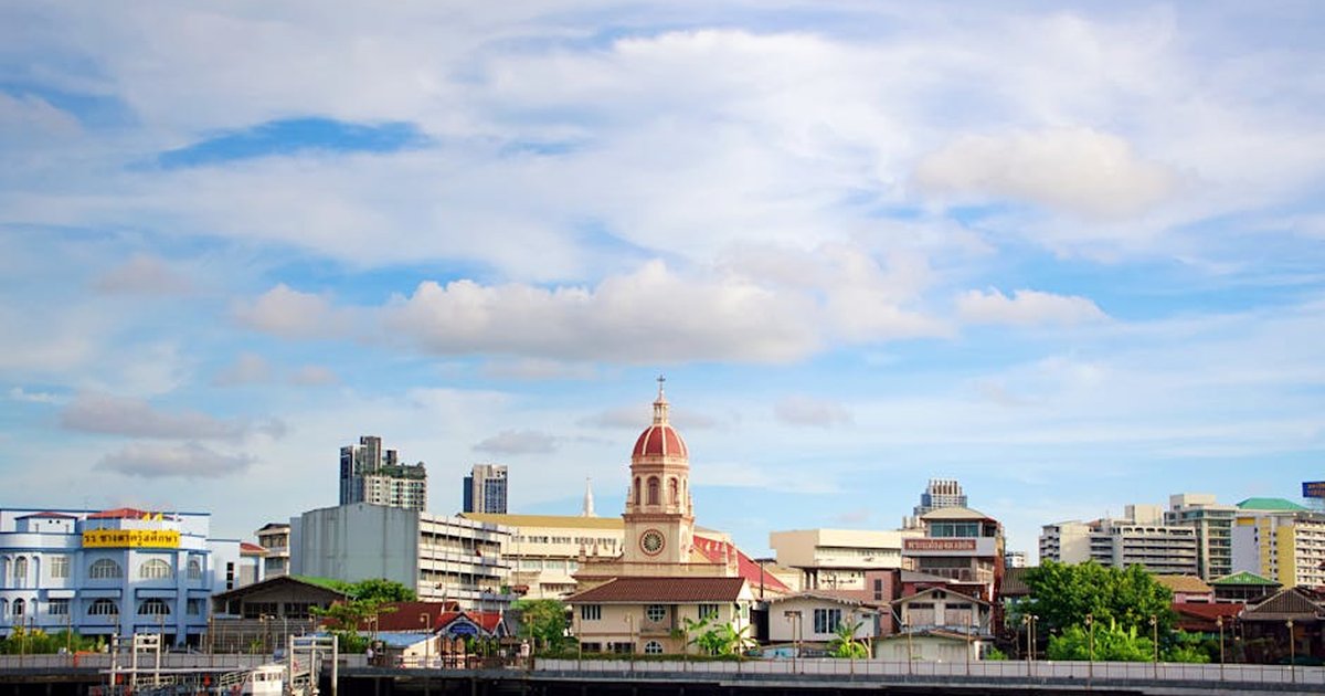 Charming riverside view in Bangkok showcasing iconic architecture under a vibrant sky.