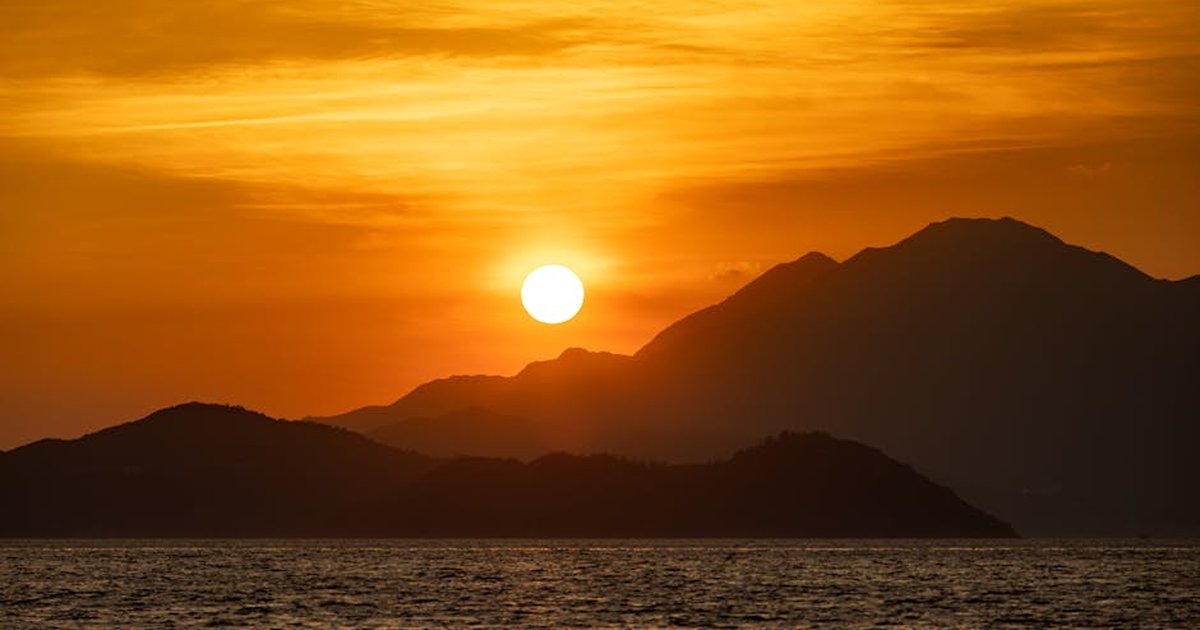 Stunning sunset view over a mountainous coastline, capturing the beauty of nature and serene sea.