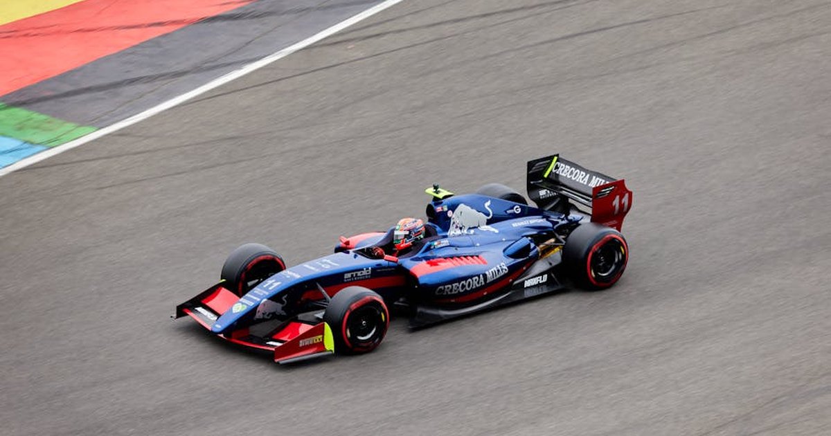 Blue race car speeding on a track with colorful markings, showcasing motorsport action.