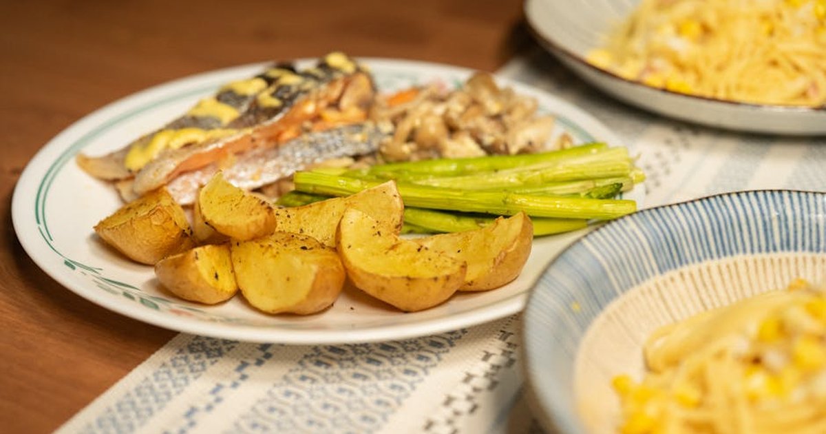 A visually appetizing serving of grilled salmon, roasted potatoes, and asparagus plated with pasta for a gourmet experience.