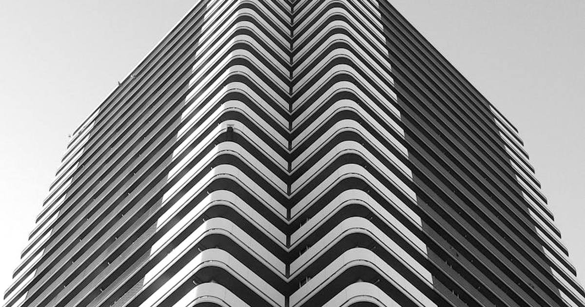 From below of black and white modern multistory building with unusual architectural design with curvy shapes and geometric balconies in city
