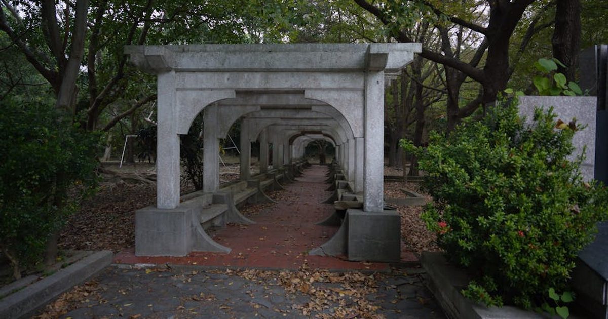 A serene stone pathway under lush trees in a quiet park setting in Hsinchu City, Taiwan.