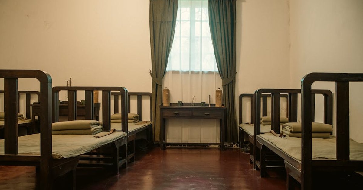 Interior view of a historic dormitory room in Meiling Palace, featuring classic wooden beds and furnishings.