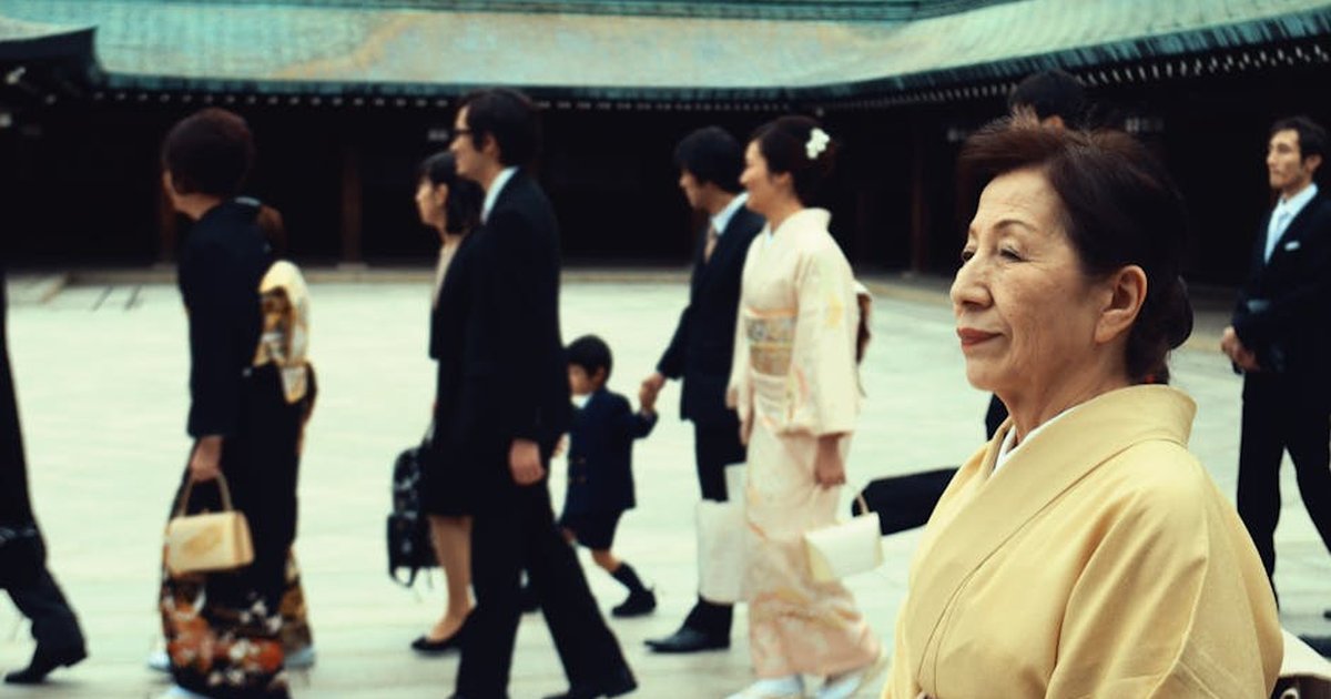 A group of people in traditional kimono participating in a Japanese ceremony outdoors.