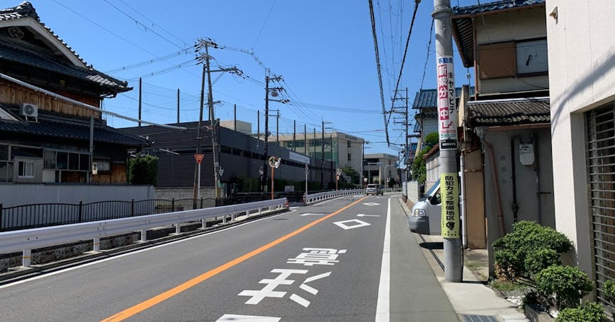Empty suburban street in Japan with traditional houses and blue sky.