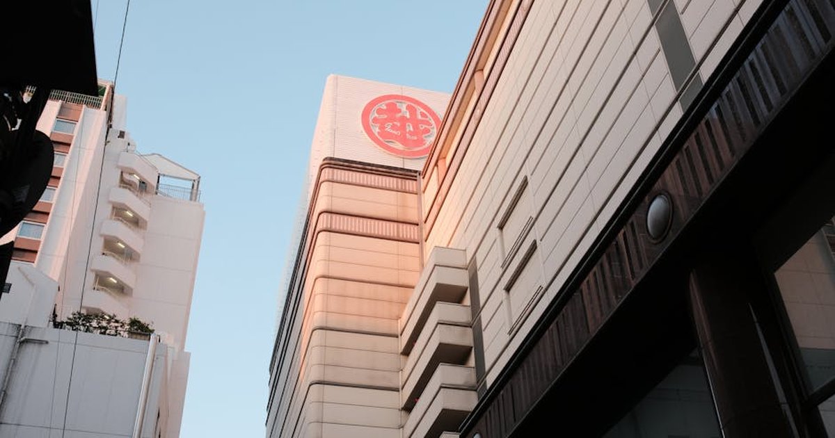 View of a modern skyscraper in an urban setting with prominent Japanese signage.