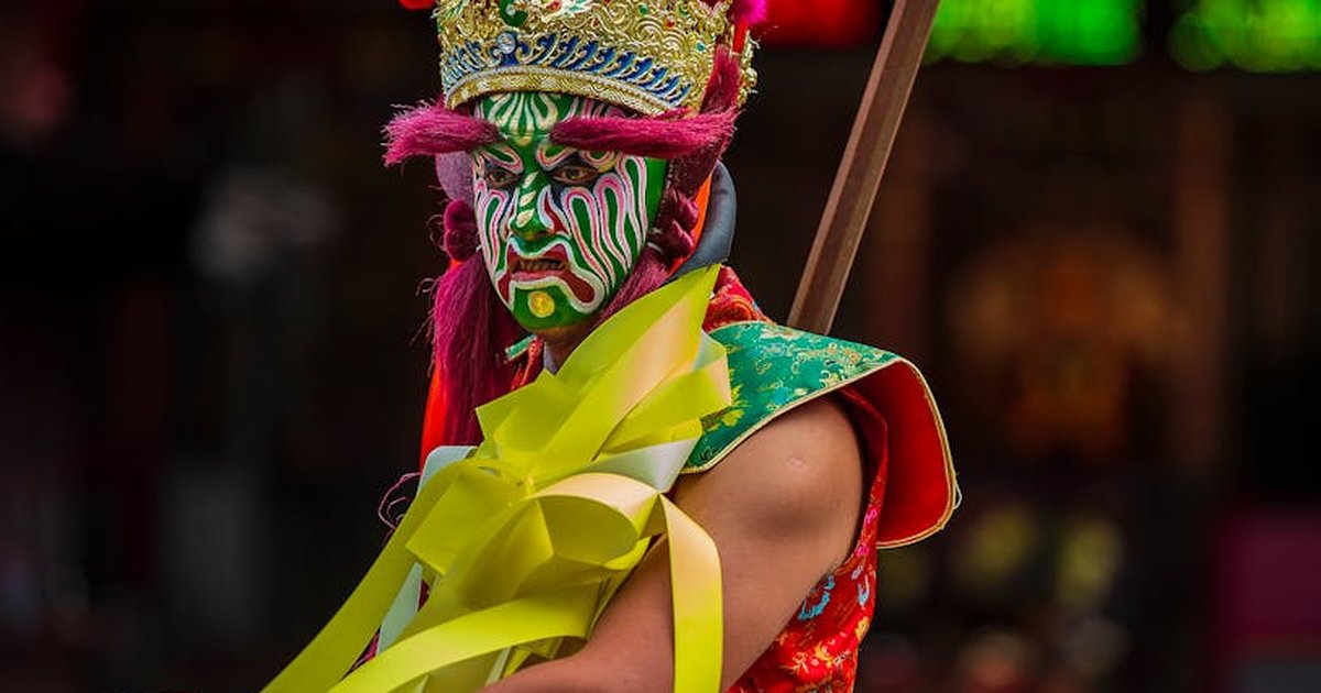 A vibrant cultural performer with intricate face paint and costume captured during a festival in Taiwan.