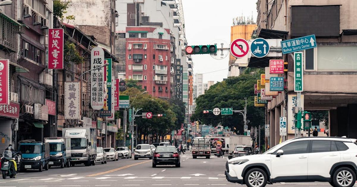 Lively urban street in Taipei, Taiwan, featuring cars, bikes, and vibrant Chinese signs.