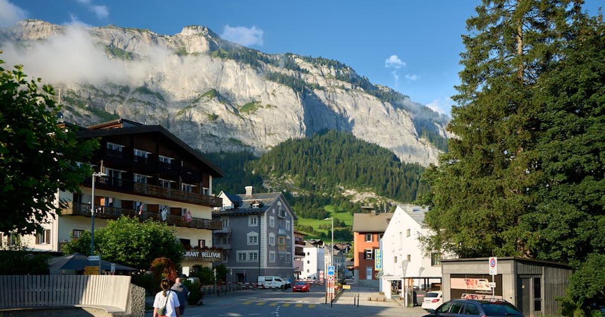 Scenic view of a mountain village with people walking under a clear blue sky.