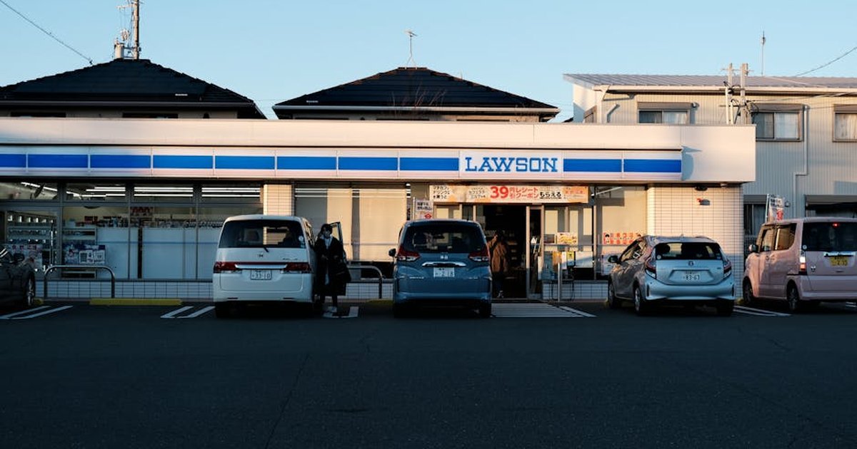 Lawson store front with parked cars at sunset in Toyohashi, Japan.
