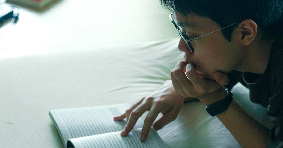 Young adult reading a book indoors in Jakarta, focusing on learning and relaxation.