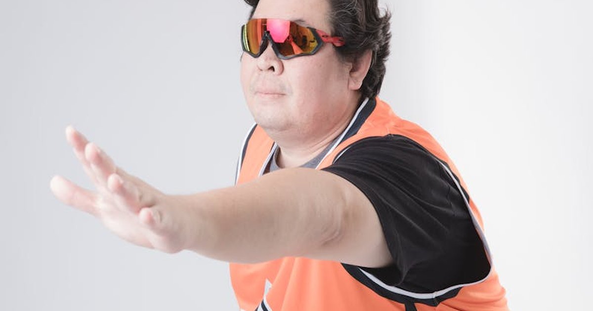 Adult man in sportswear posing with VR glasses in a studio setting on a white background.