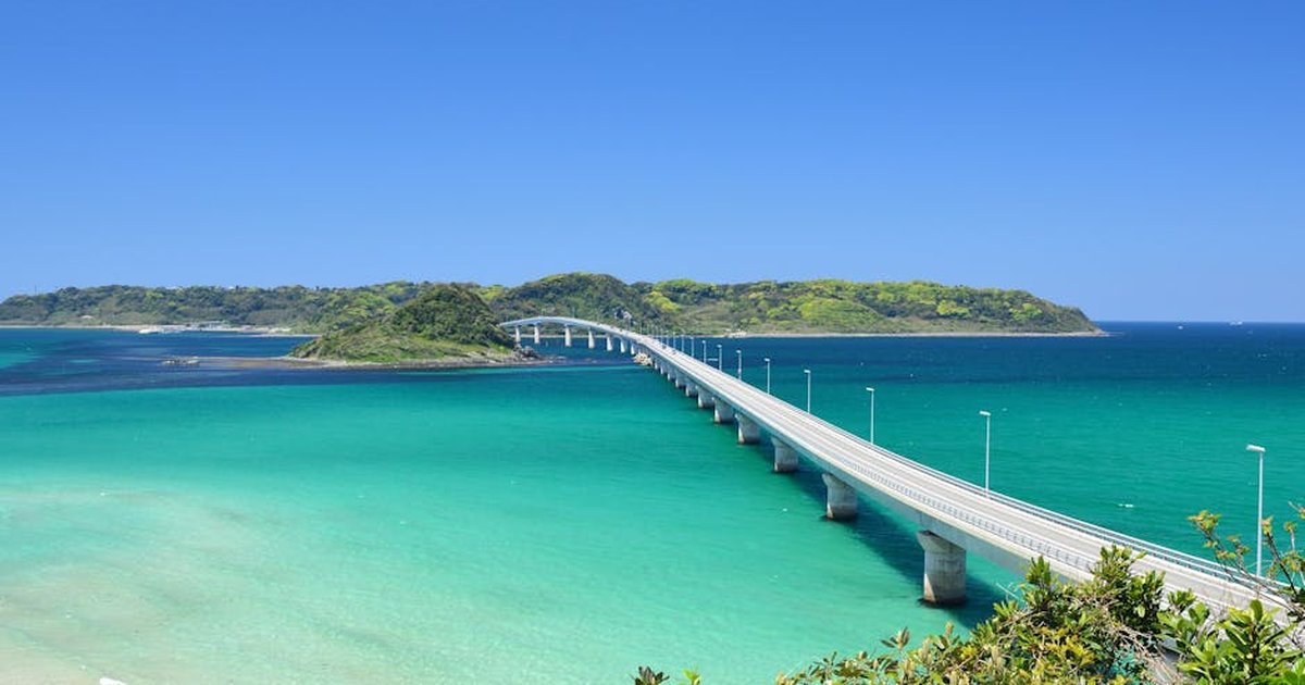 Scenic view of Tsunoshima Bridge spanning turquoise waters in Yamaguchi, Japan under a clear blue sky.