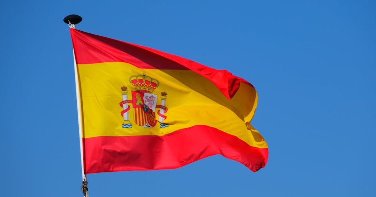 Bright Spanish flag waving against a clear blue sky, showcasing national pride.