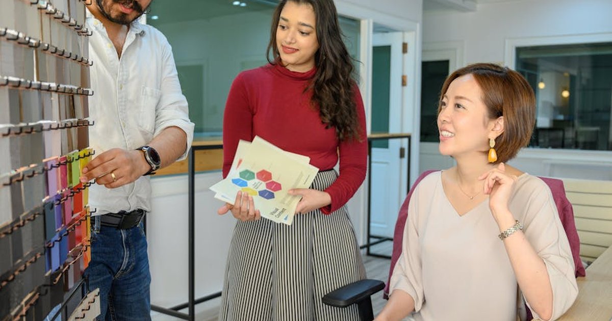 Three colleagues discussing design samples in a modern office, promoting teamwork and creativity.