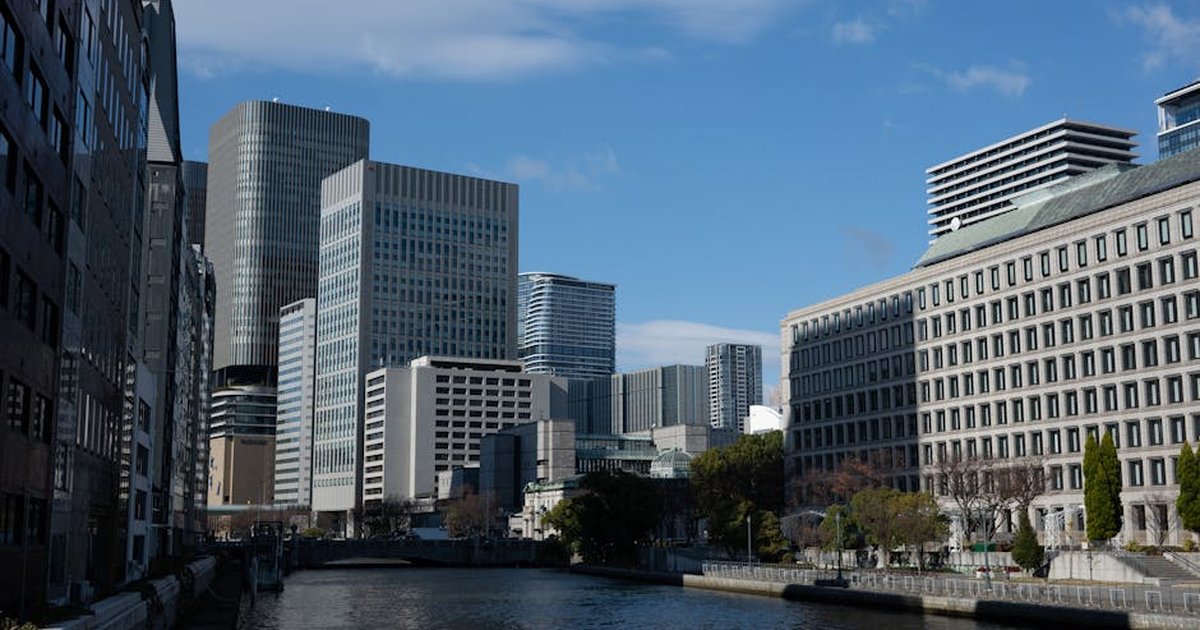 Urban landscape of Osaka featuring modern architecture along a serene river under a blue sky.
