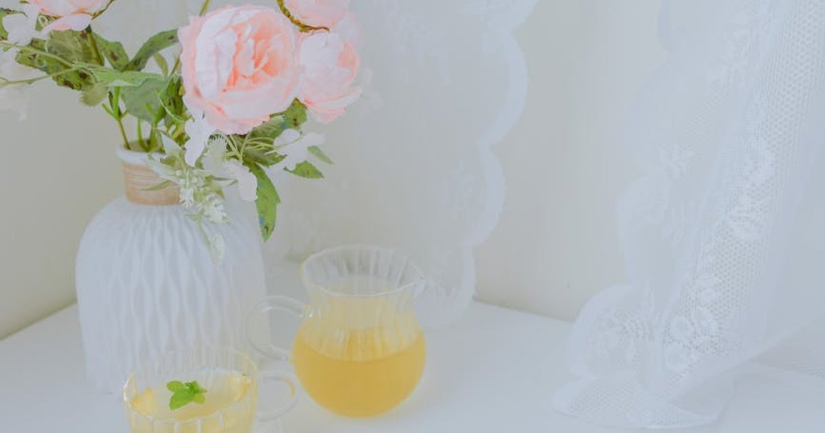 Delicate floral arrangement in vase with tea cups on white table, perfect for home decor themes.