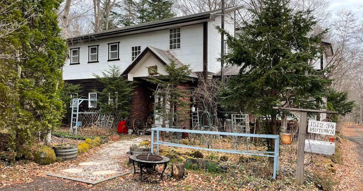 A charming rustic house nestled among trees during fall, showcasing lush greenery and quaint surroundings.