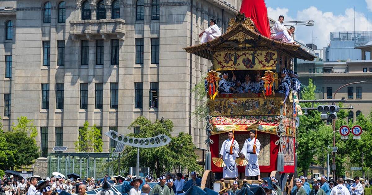 Colorful festival float with participants in traditional attire during a sunny parade in Japan.