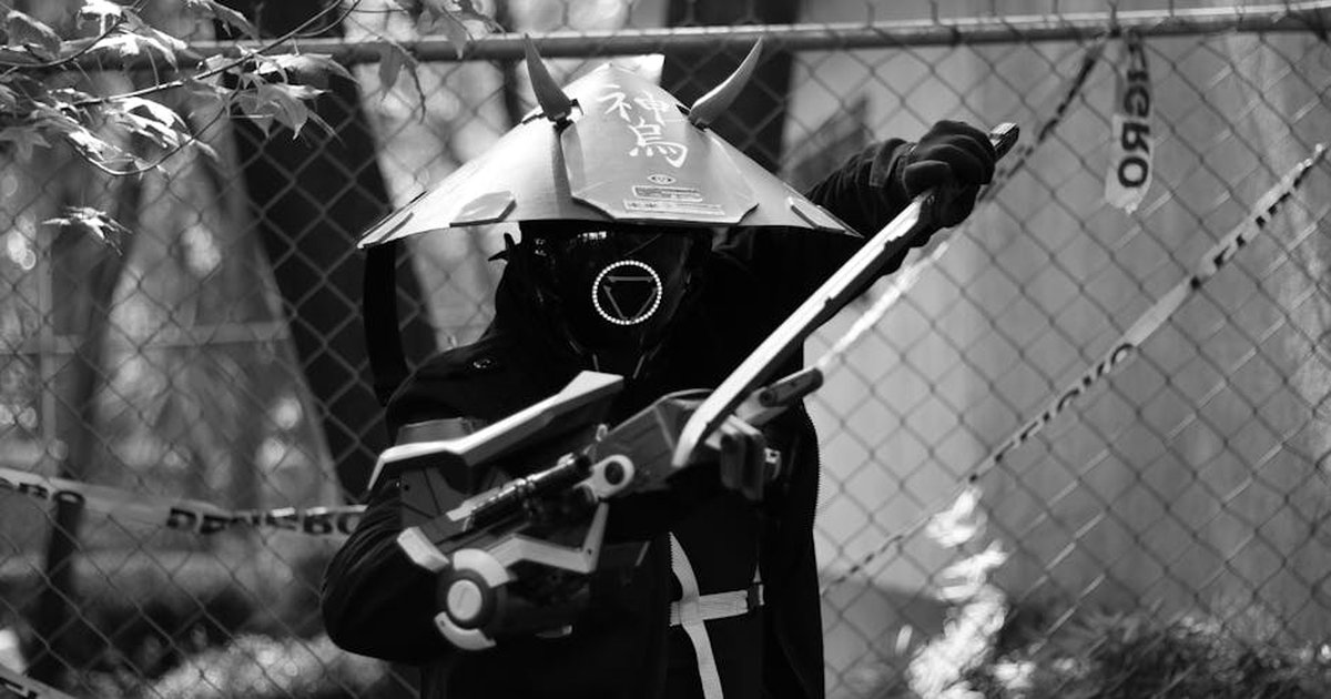 A striking black and white photo of a futuristic samurai warrior holding a weapon, wearing a helmet with Japanese text.