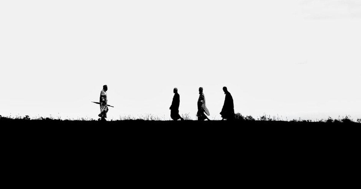 Black and white silhouette of men in traditional clothing walking on a field in Bangladesh.