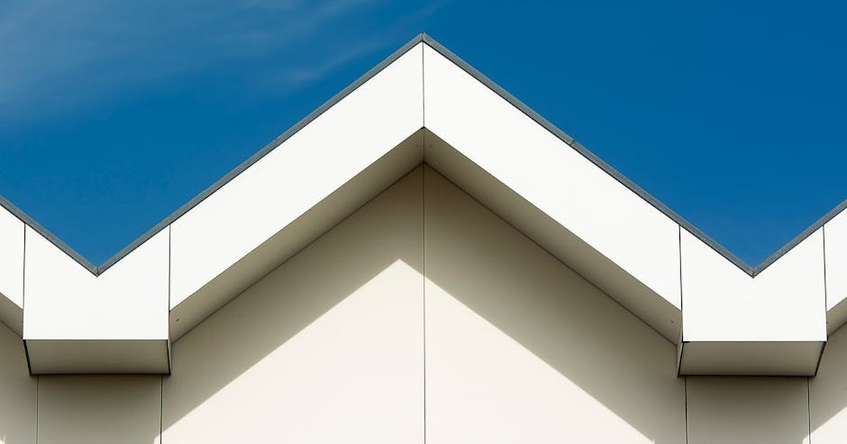 A sharp-edged modern roof structure contrasts with a clear blue sky, showcasing contemporary architecture.